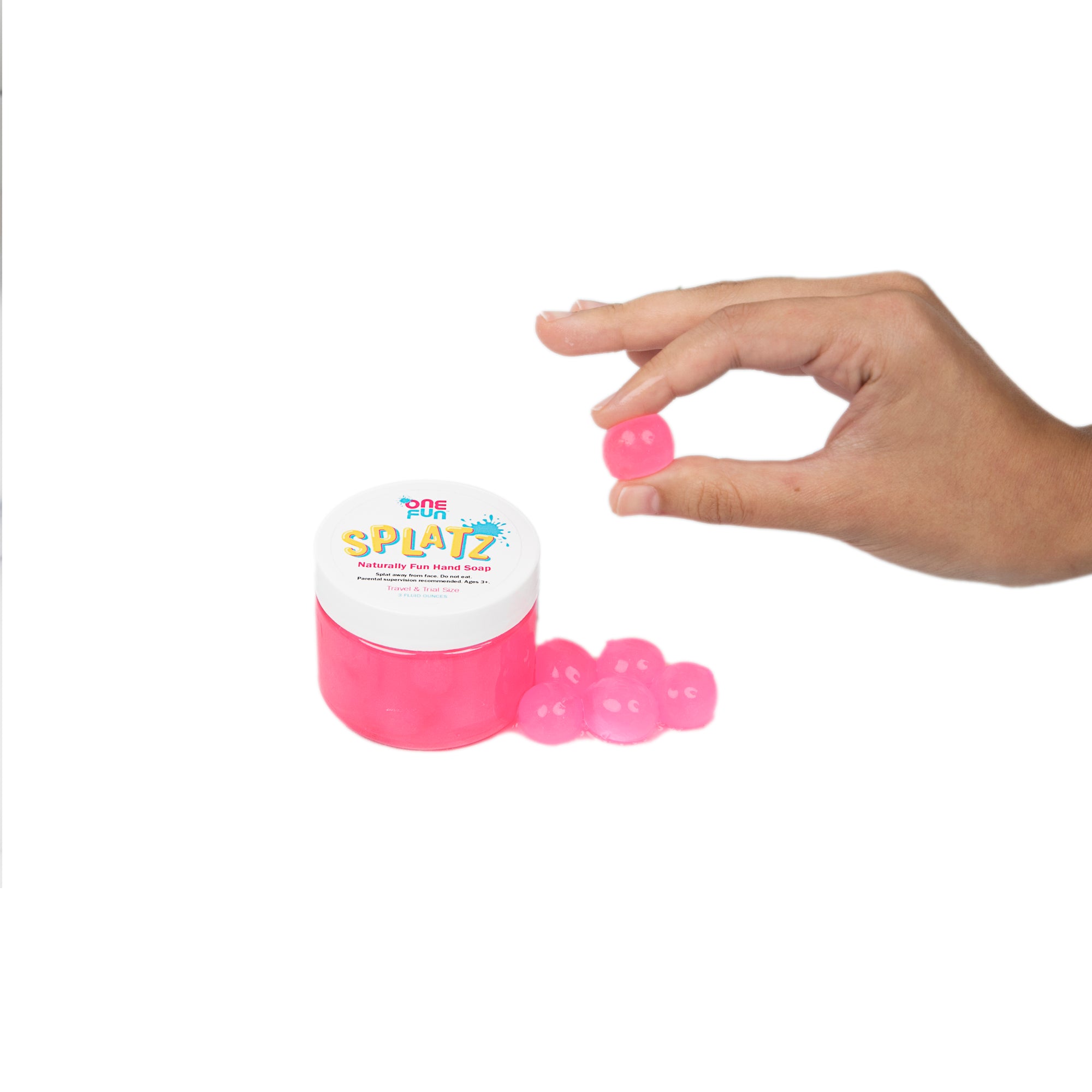 A 3oz jar of pink bursting soap bubbles and a hand holding one pink bursting soap bubble